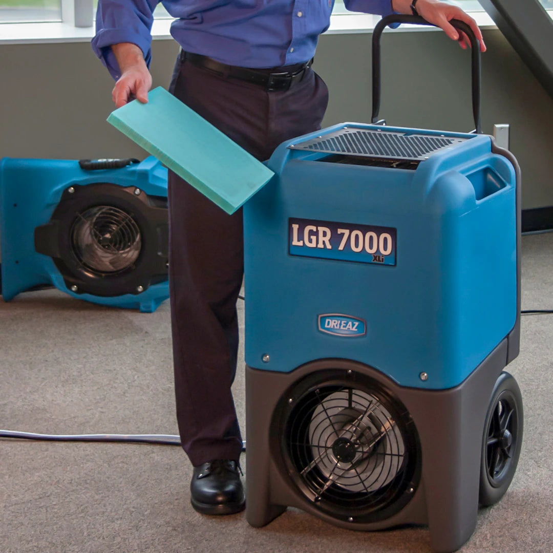 Person standing next to a blue Dri-Eaz LGR 7000 dehumidifier in an indoor setting.