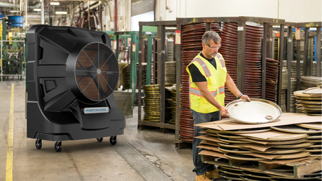 Large industrial portable air conditioner in a warehouse setting with a worker handling materials.