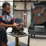 Mechanic working on a gear system in a workshop with a Portacool unit in the foreground.